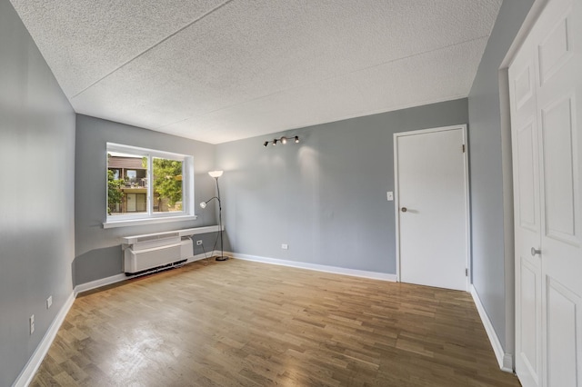 5550 Astor Ln Unit 214, Rolling Meadows, IL 60008 - unfurnished room with a textured ceiling, wood finished floors, and a wall mounted air conditioner