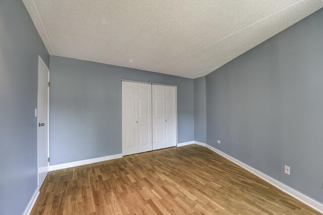 5550 Astor Ln Unit 214, Rolling Meadows, IL 60008 - unfurnished bedroom with wood finished floors, a textured ceiling, and a closet