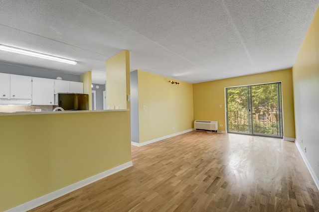 5550 Astor Ln Unit 214, Rolling Meadows, IL 60008 - unfurnished living room featuring light wood-style flooring, a textured ceiling, and a wall mounted air conditioner