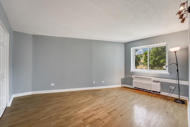 5550 Astor Ln Unit 214, Rolling Meadows, IL 60008 - unfurnished bedroom featuring a wall unit AC, wood finished floors, and a textured ceiling