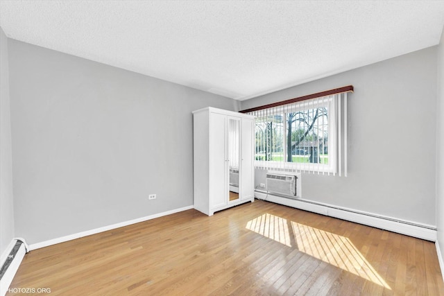 9205 Potter Rd Unit 1C, Des Plaines, IL 60016 - unfurnished room featuring a baseboard heating unit, a baseboard radiator, wood finished floors, a textured ceiling, and an AC wall unit