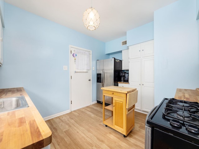 4130 N Oketo Ave, Norridge, IL 60706 - kitchen featuring wood counters, stainless steel fridge, range with gas stovetop, light wood finished floors, and hanging light fixtures