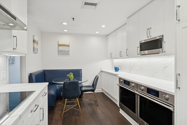 680 N Lake Shore Dr Unit 321, Chicago, IL 60611 - kitchen with appliances with stainless steel finishes, wall chimney exhaust hood, dark wood-style flooring, recessed lighting, and backsplash