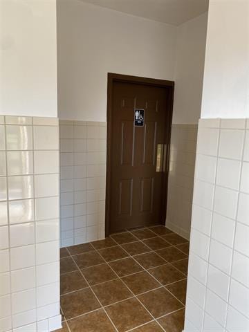 5918 Park Ridge Rd, Loves Park, IL 61111 - hallway with tile walls, dark tile patterned flooring, and a wainscoted wall
