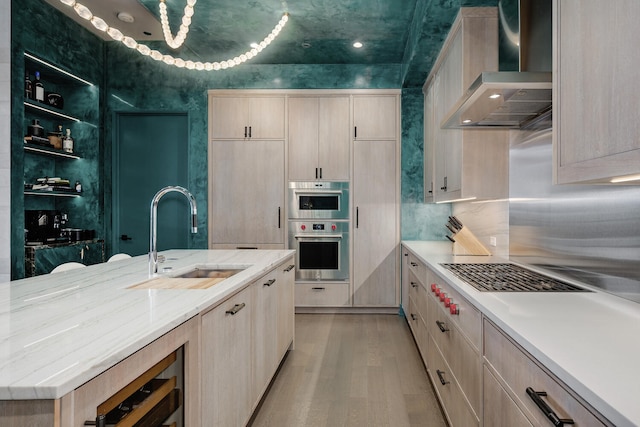 1550 N Clark St Unit 302, Chicago, IL 60610 - kitchen with wall chimney exhaust hood, light brown cabinetry, stainless steel appliances, light wood finished floors, and light stone counters