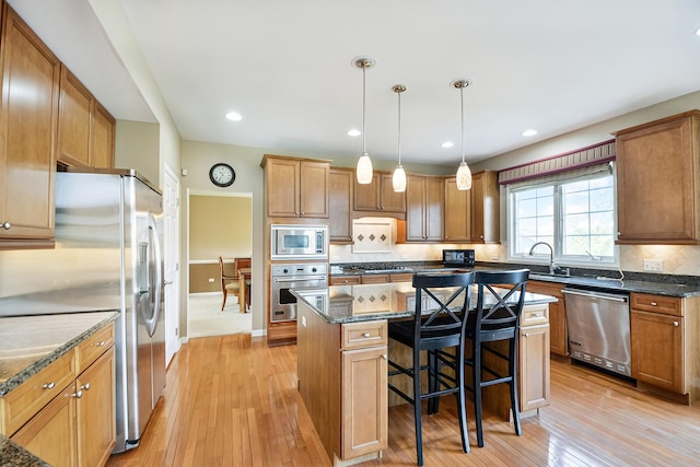 40 Open Pkwy N, Hawthorn Woods, IL 60047 - kitchen with appliances with stainless steel finishes, a kitchen island, light wood-type flooring, a kitchen bar, and dark stone counters