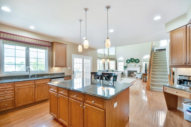 40 Open Pkwy N, Hawthorn Woods, IL 60047 - kitchen featuring a kitchen island, a warm lit fireplace, backsplash, light wood-type flooring, and dark stone counters