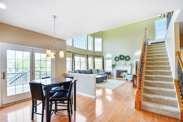 40 Open Pkwy N, Hawthorn Woods, IL 60047 - dining area featuring stairs, light wood-style flooring, a lit fireplace, a chandelier, and crown molding