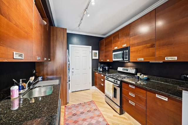 2950 W Cortland St Unit 2, Chicago, IL 60647 - kitchen featuring appliances with stainless steel finishes, modern cabinets, light wood finished floors, rail lighting, and brown cabinetry