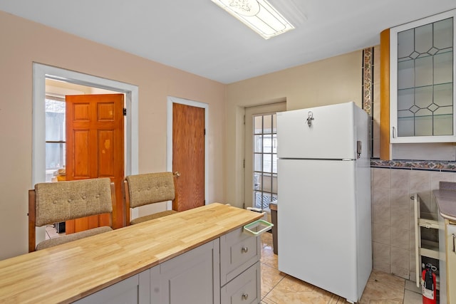 3609 S Leavitt St, Chicago, IL 60609 - kitchen with freestanding refrigerator, butcher block countertops, light tile patterned floors, and tile walls