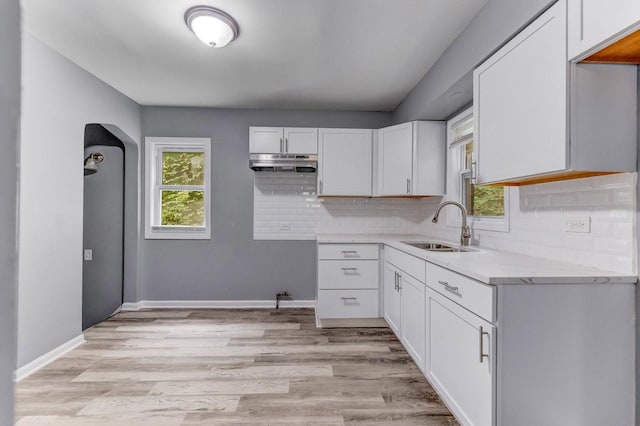 9019 S Justine St, Chicago, IL 60620 - kitchen featuring under cabinet range hood, backsplash, white cabinets, light wood-style flooring, and arched walkways