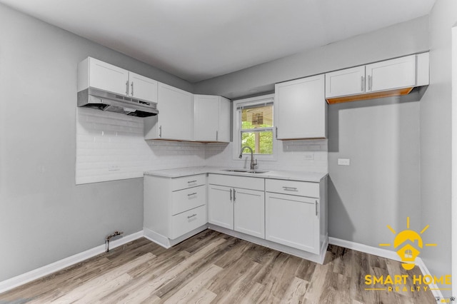 9019 S Justine St, Chicago, IL 60620 - kitchen featuring under cabinet range hood, light wood-style floors, white cabinetry, light countertops, and tasteful backsplash
