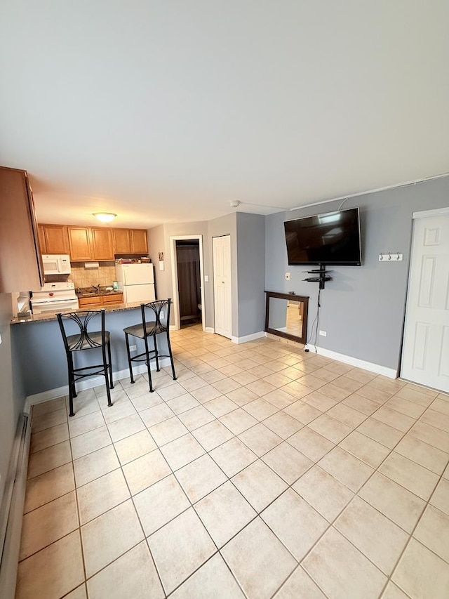 4620 Fishermans Ter Unit Ge, Lyons, IL 60534 - kitchen featuring white appliances, light tile patterned floors, baseboard heating, a peninsula, and a kitchen bar
