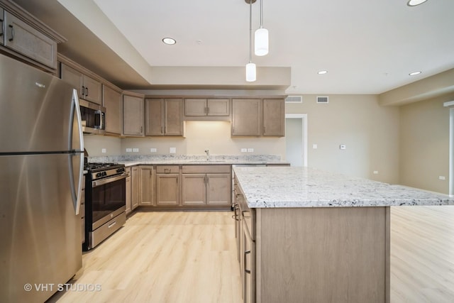 2150 Founders Dr Unit P109, Northbrook, IL 60062 - kitchen featuring appliances with stainless steel finishes, light wood-type flooring, a kitchen island, light stone countertops, and hanging light fixtures