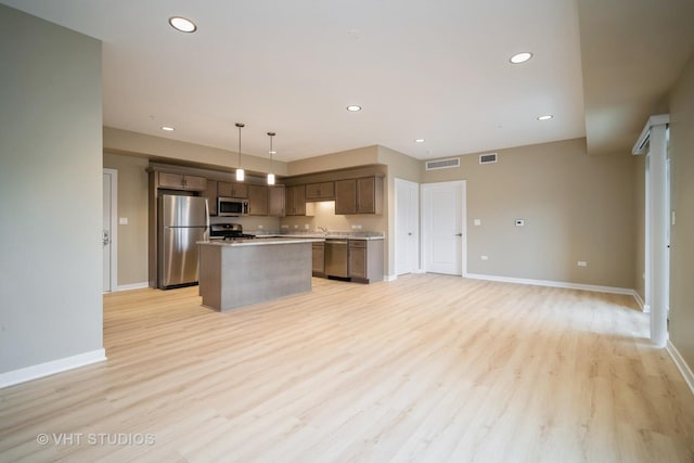 2150 Founders Dr Unit P109, Northbrook, IL 60062 - kitchen featuring stainless steel appliances, a center island, light wood-style flooring, light countertops, and decorative light fixtures