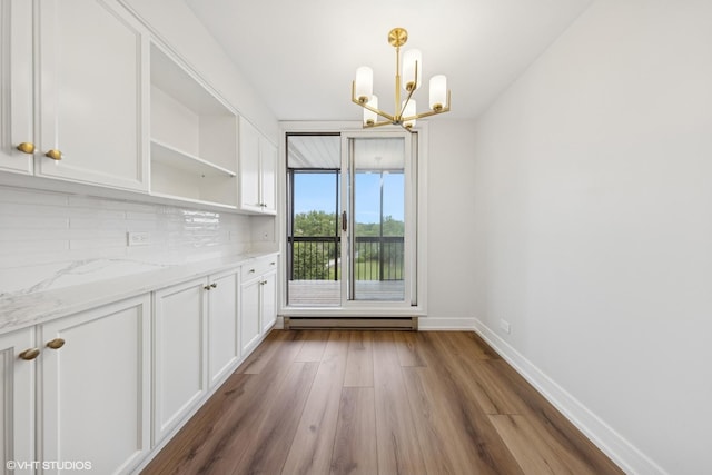 1140 Old Mill Rd Unit 505F, Hinsdale, IL 60521 - unfurnished dining area featuring a chandelier, a baseboard radiator, and wood finished floors