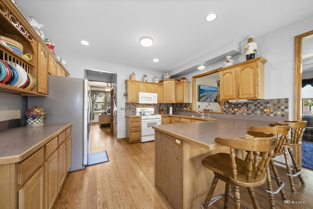 14879 Harbor Dr, Oak Forest, IL 60452 - kitchen with white appliances, a breakfast bar area, a peninsula, backsplash, and light wood-style flooring