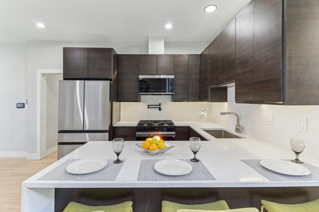 2307 N Avers Ave Unit 2, Chicago, IL 60647 - kitchen featuring stainless steel appliances, dark brown cabinetry, light countertops, a peninsula, and recessed lighting