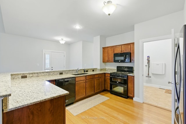 15701 Cove Cir, Plainfield, IL 60544 - kitchen featuring black appliances, light stone counters, light wood finished floors, and brown cabinetry