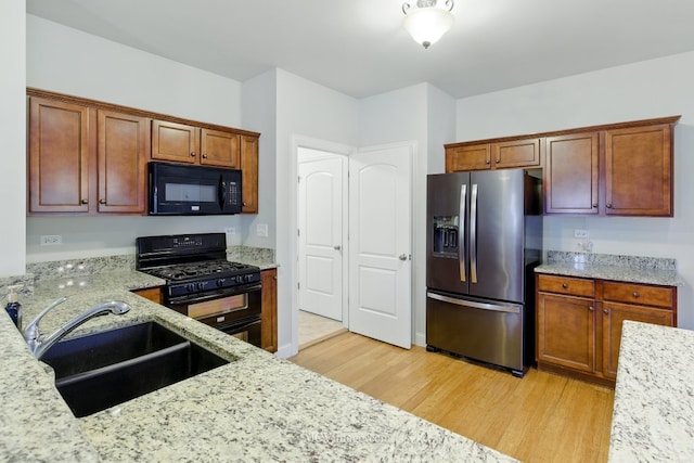 15701 Cove Cir, Plainfield, IL 60544 - kitchen featuring black appliances, light wood-type flooring, light stone countertops, and brown cabinetry