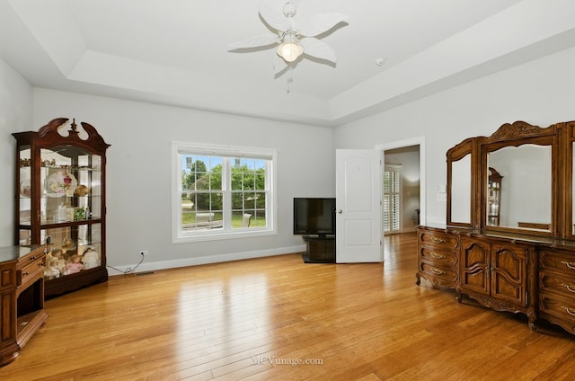 15701 Cove Cir, Plainfield, IL 60544 - unfurnished living room with a tray ceiling, ceiling fan, and light wood-style flooring