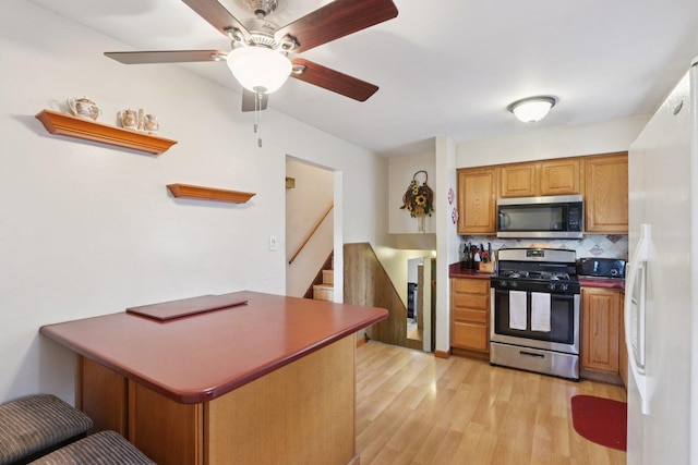 10956 S Nagle Ave, Worth, IL 60482 - kitchen with appliances with stainless steel finishes, light wood-style flooring, backsplash, ceiling fan, and a peninsula