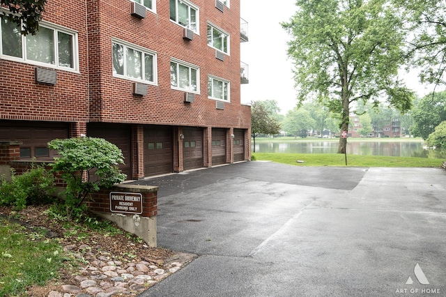 101 N Peartree Ln Unit 101, Arlington Heights, IL 60004 - view of property featuring asphalt driveway, a water view, and a garage