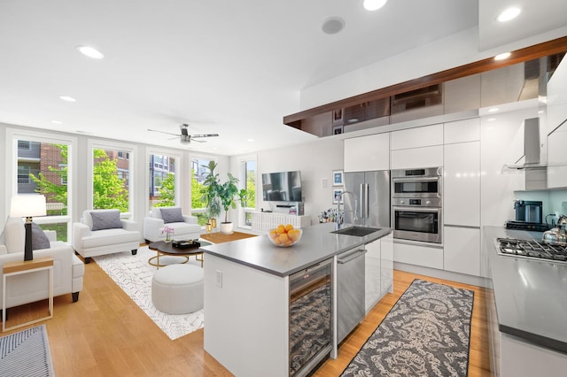 1008 N Larrabee St Unit 2S, Chicago, IL 60610 - kitchen with modern cabinets, appliances with stainless steel finishes, white cabinets, a center island with sink, and light wood finished floors