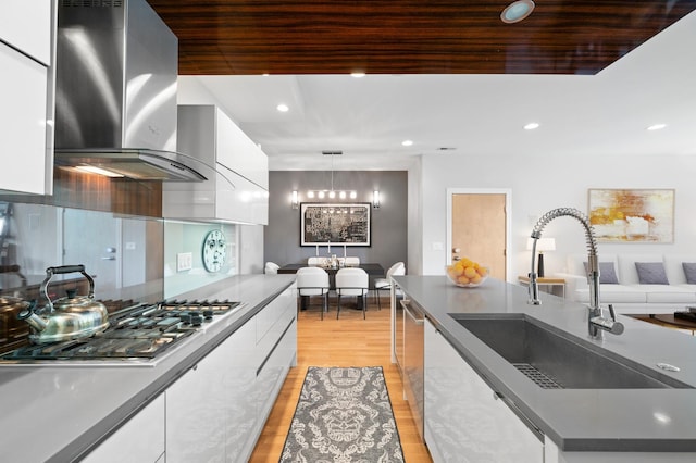 1008 N Larrabee St Unit 2S, Chicago, IL 60610 - kitchen with modern cabinets, wall chimney exhaust hood, stainless steel gas cooktop, white cabinetry, and light wood-style floors