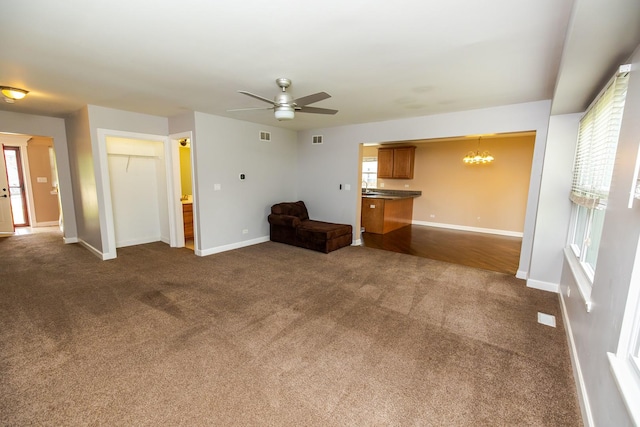 340 Hubbard Ave, Elgin, IL 60123 - unfurnished living room featuring a chandelier, dark carpet, a ceiling fan, and healthy amount of natural light
