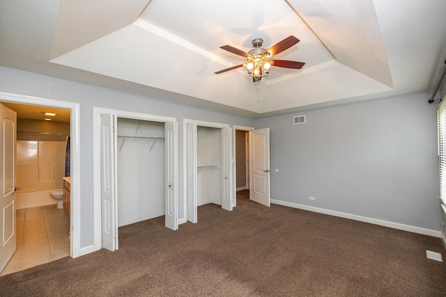 340 Hubbard Ave, Elgin, IL 60123 - unfurnished bedroom with a tray ceiling, carpet, two closets, ensuite bathroom, and ceiling fan