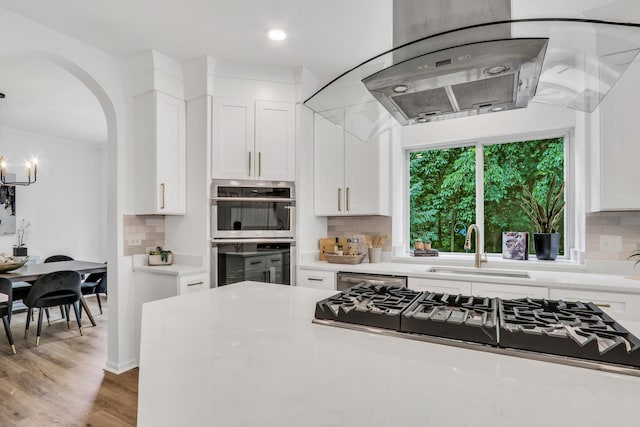 7612 Cascade Way, Gurnee, IL 60031 - kitchen with appliances with stainless steel finishes, arched walkways, white cabinetry, tasteful backsplash, and island range hood
