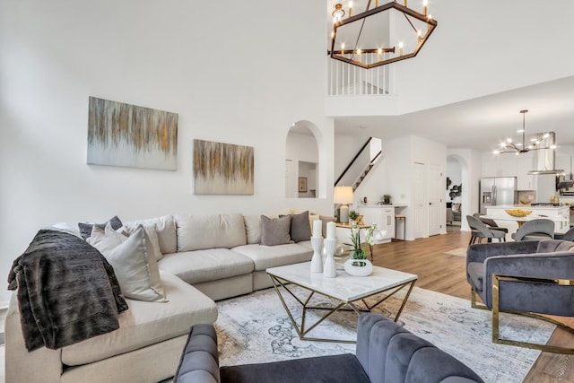 7612 Cascade Way, Gurnee, IL 60031 - living area featuring arched walkways, a chandelier, light wood finished floors, a high ceiling, and stairs