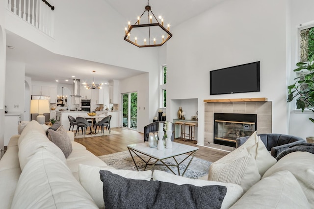 7612 Cascade Way, Gurnee, IL 60031 - living area with a chandelier, light wood-style flooring, a towering ceiling, a tiled fireplace, and recessed lighting