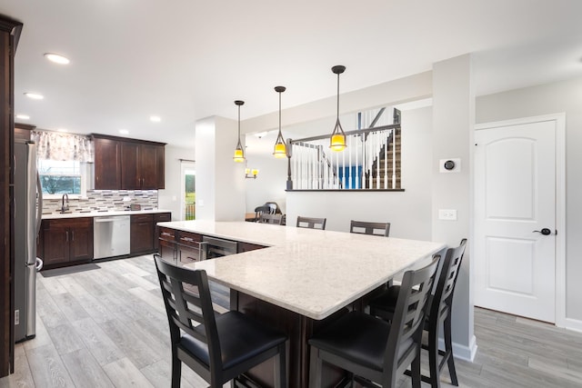 1792 Autumn Woods Ln, Romeoville, IL 60446 - kitchen with appliances with stainless steel finishes, dark brown cabinets, light wood finished floors, a breakfast bar area, and backsplash