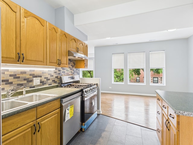 1729 E 67th St Unit 2E, Chicago, IL 60649 - kitchen with appliances with stainless steel finishes, under cabinet range hood, decorative backsplash, dark countertops, and light tile patterned flooring