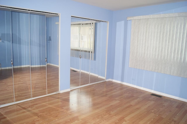 4184 Cove Ln Unit D, Glenview, IL 60025 - unfurnished bedroom featuring wood finished floors and two closets