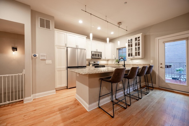 3457 N Whipple St, Chicago, IL 60618 - kitchen featuring appliances with stainless steel finishes, a breakfast bar area, light wood finished floors, glass insert cabinets, and recessed lighting