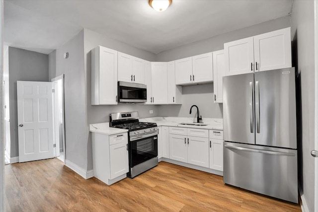 4336 W Adams St, Chicago, IL 60624 - kitchen with appliances with stainless steel finishes, light wood-style flooring, white cabinets, and light stone countertops