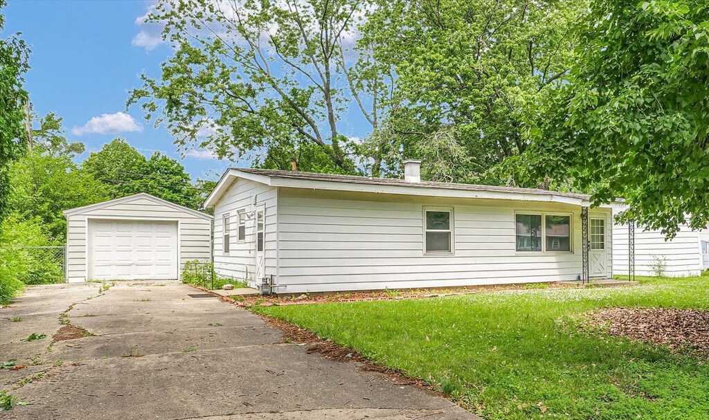 1313 Hollycrest Dr, Champaign, IL 61821 - view of side of property with an outbuilding, concrete driveway, a detached garage, and a yard