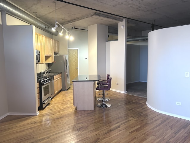 6 S Laflin St Unit 920, Chicago, IL 60607 - kitchen featuring appliances with stainless steel finishes, a breakfast bar area, light wood-style flooring, dark countertops, and light brown cabinets