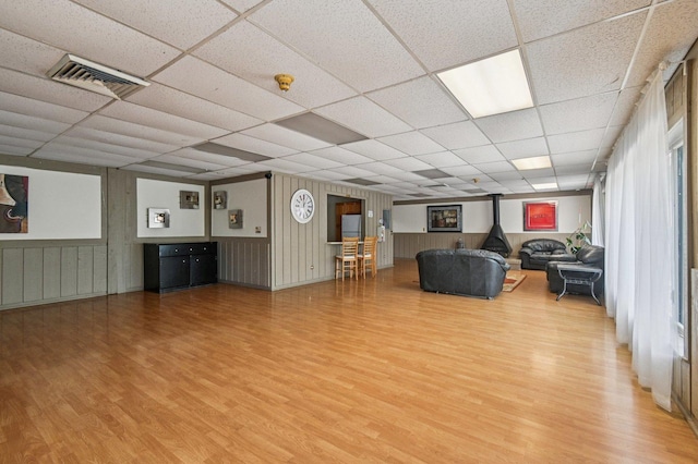 9S240 Lake Dr Unit 17-207B, Willowbrook, IL 60527 - living room featuring light wood-style flooring, a paneled ceiling, a wood stove, and wainscoting