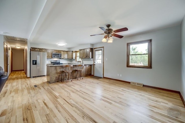 24460 Easy St, Plainfield, IL 60586 - kitchen featuring appliances with stainless steel finishes, light wood finished floors, a kitchen breakfast bar, and ceiling fan