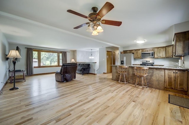 24460 Easy St, Plainfield, IL 60586 - kitchen featuring appliances with stainless steel finishes, light wood-type flooring, a peninsula, brown cabinetry, and a ceiling fan