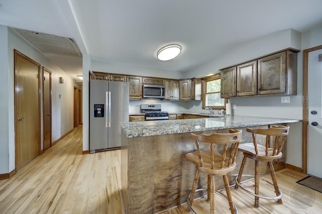 24460 Easy St, Plainfield, IL 60586 - kitchen with stainless steel appliances, a peninsula, light wood-style floors, and light stone counters