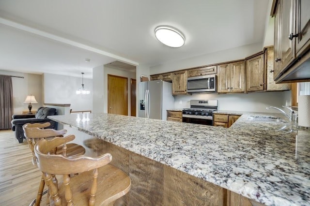 24460 Easy St, Plainfield, IL 60586 - kitchen with stainless steel appliances, light stone counters, a peninsula, a breakfast bar, and brown cabinets