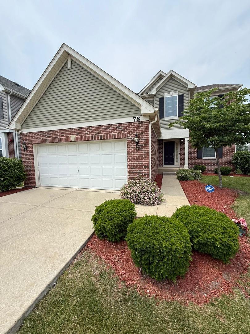 view of front of home featuring brick siding, driveway, and a garage