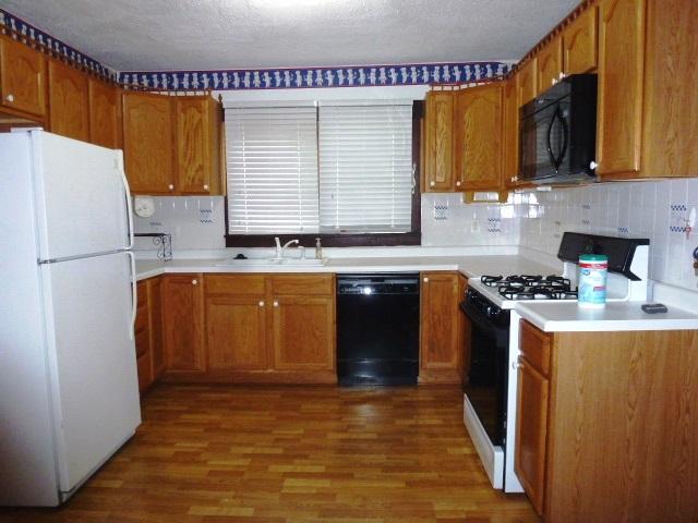 503 N Linden St, Clinton, IL 61727 - kitchen featuring black appliances, wood finished floors, brown cabinets, and a textured ceiling