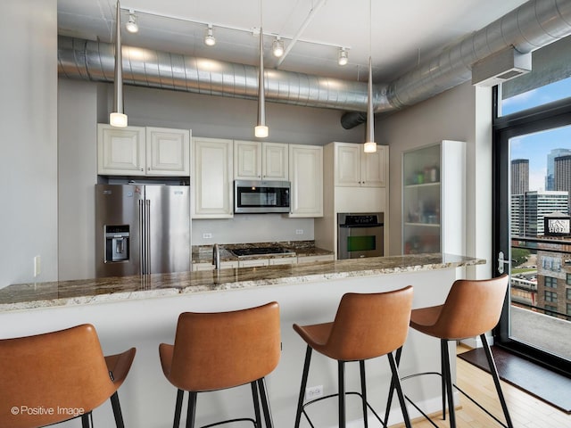 740 W Fulton St Unit 1202, Chicago, IL 60661 - kitchen featuring appliances with stainless steel finishes, a kitchen breakfast bar, light wood finished floors, light stone counters, and white cabinetry