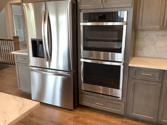 12415 Foxborough Dr, Mokena, IL 60448 - kitchen with stainless steel appliances, backsplash, light wood-style flooring, and light stone counters